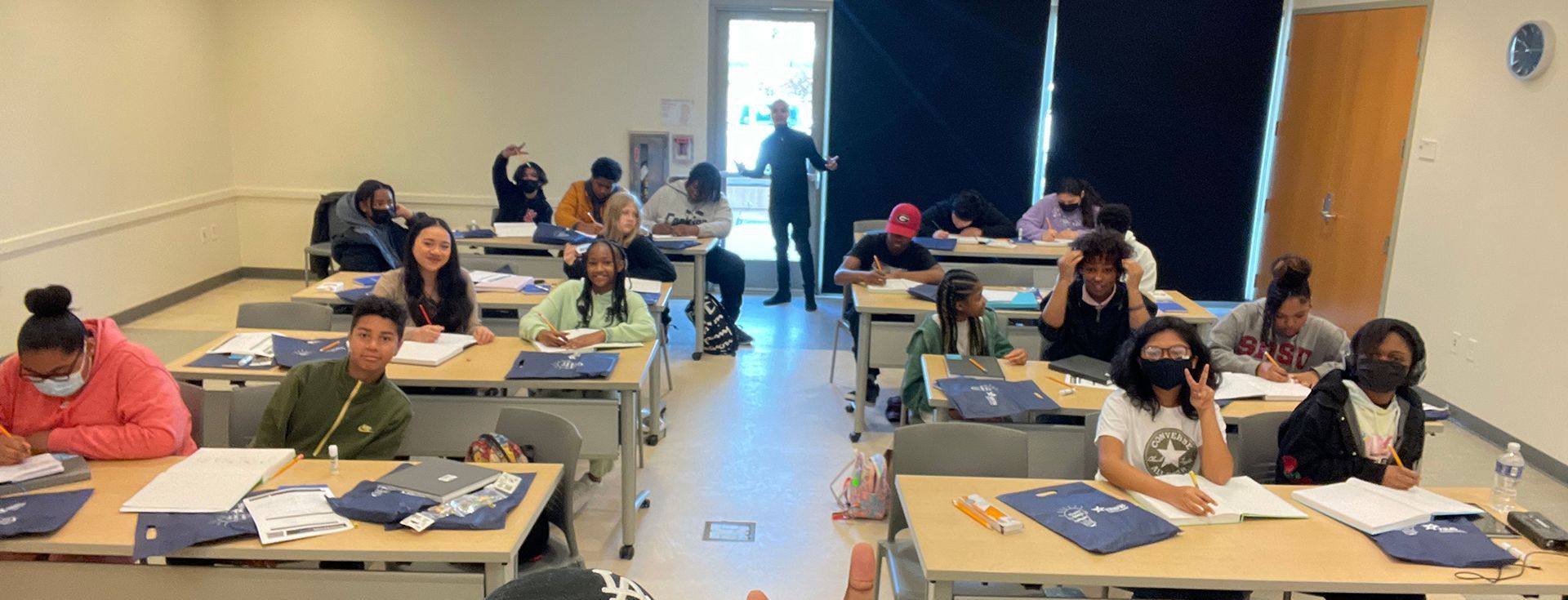 A group of people are sitting at tables in a classroom.