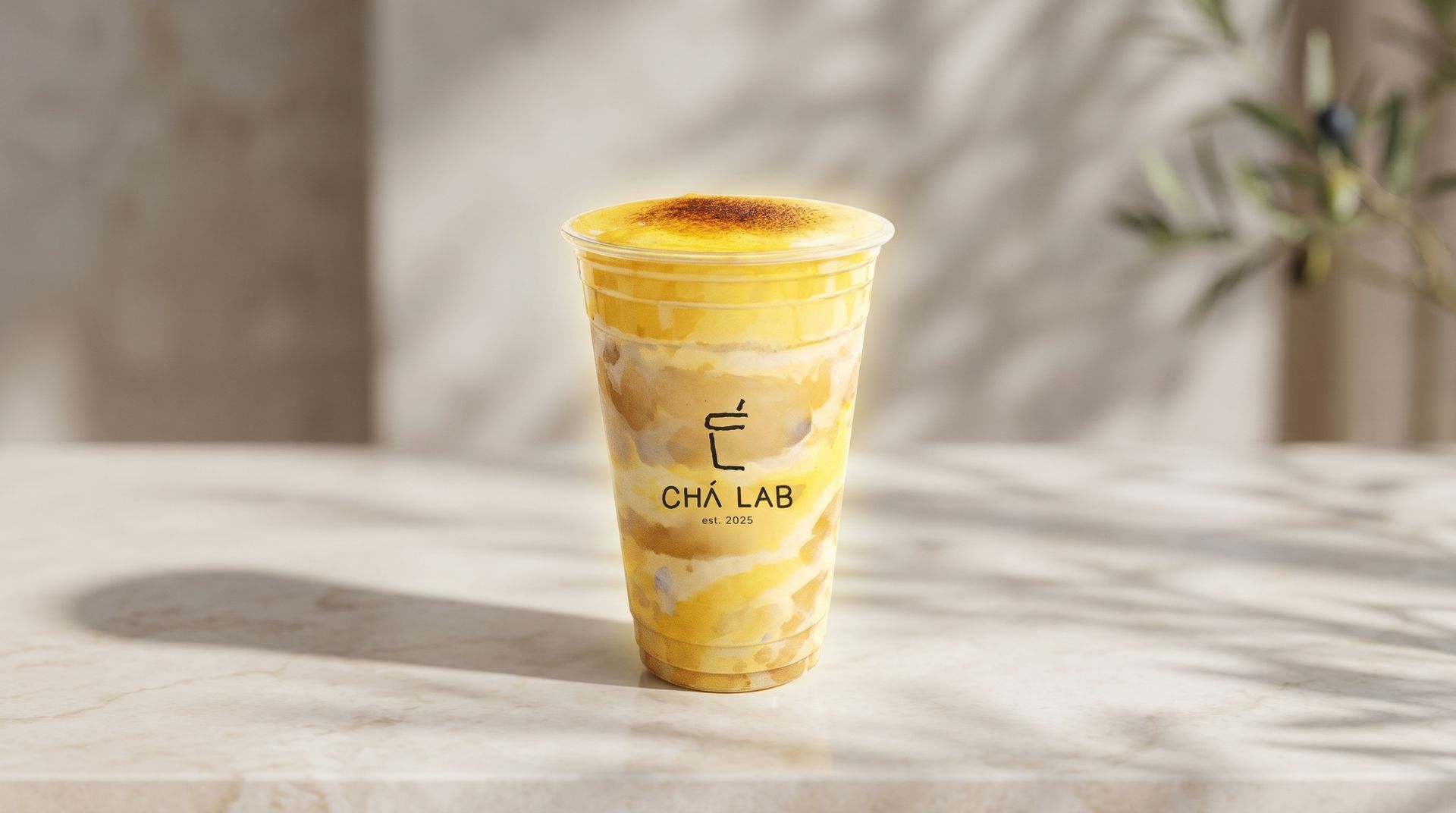 Yellow iced drink in a clear cup with a lid and straw on a sunlit tabletop.