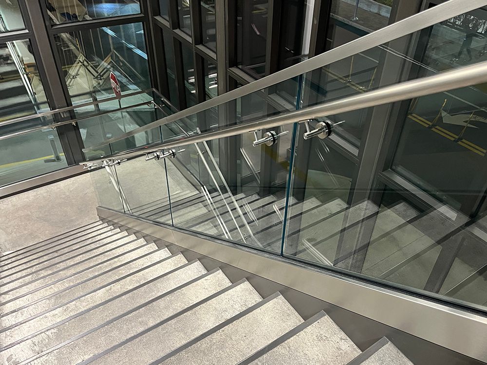 Glass-railed airport stairs with sturdy metal rails and concrete steps
