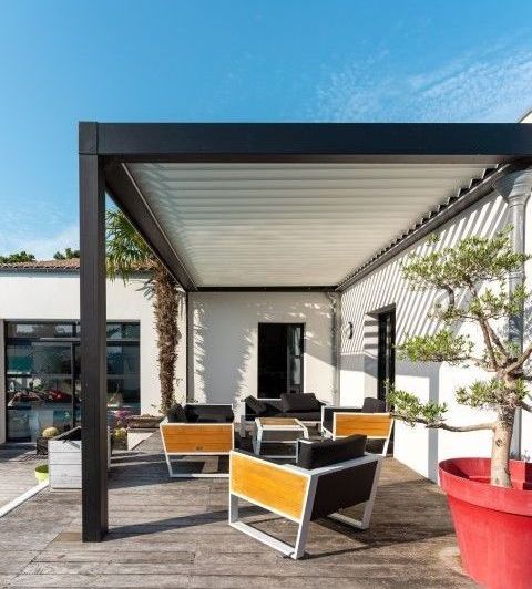 Modern outdoor patio featuring pergola, seating, and a grill