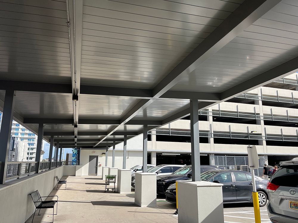 Cars sheltered by a grocery store's walkway canopy