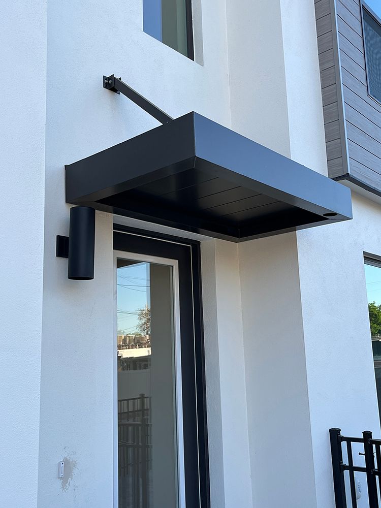 A black cantilever awning with drainage on a white facade