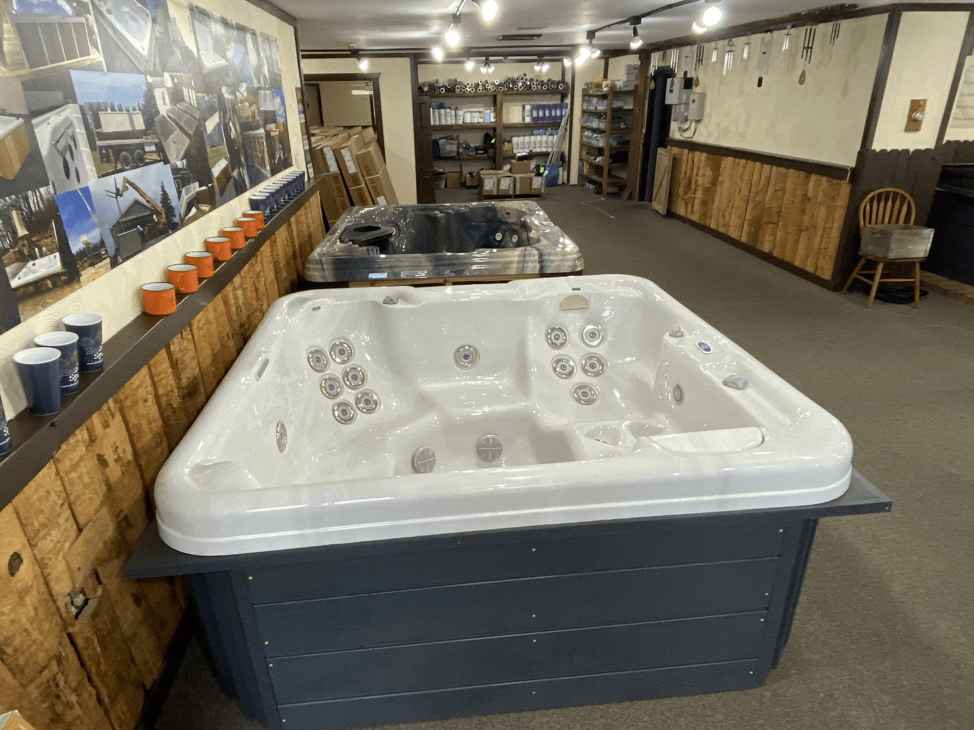 Hot tub in a garage, with a brown wood-like exterior and white interior, ready for installation.