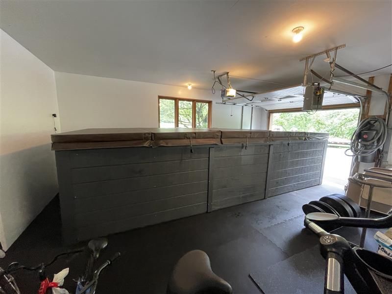 Long, dark-gray hot tub inside a garage. Two bikes and open garage door visible.