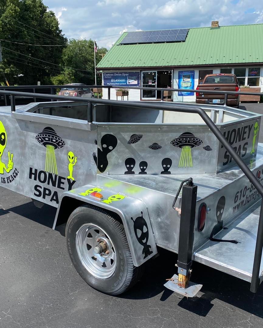Silver trailer with alien-themed graphics, parked in front of a store.
