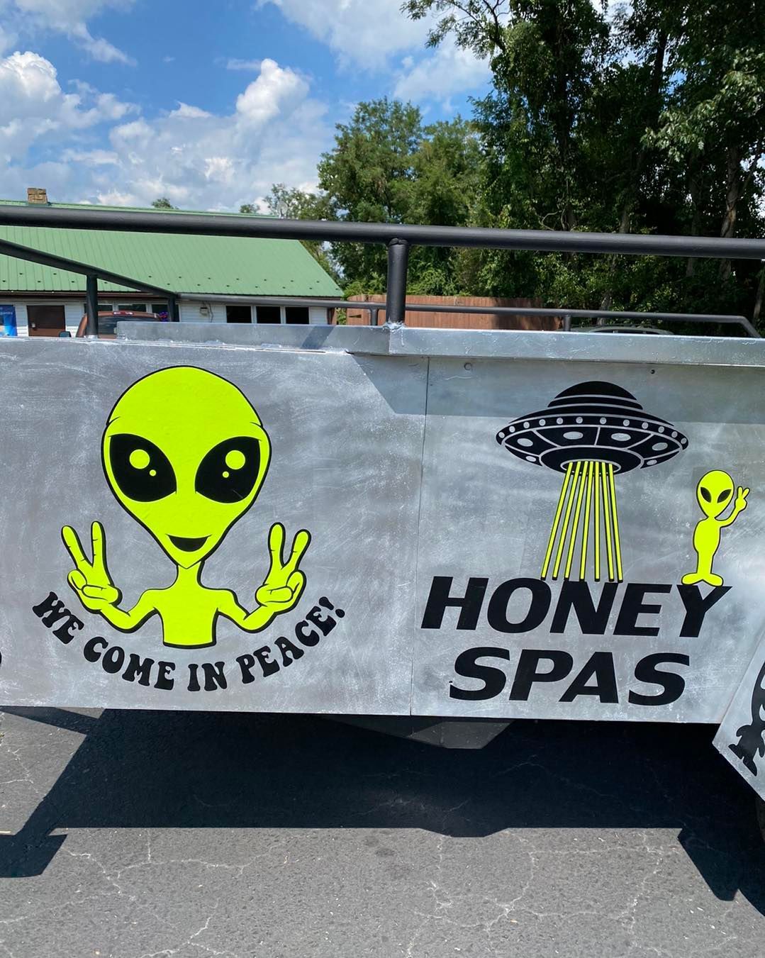 A sign on a silver structure with alien graphics that read, 