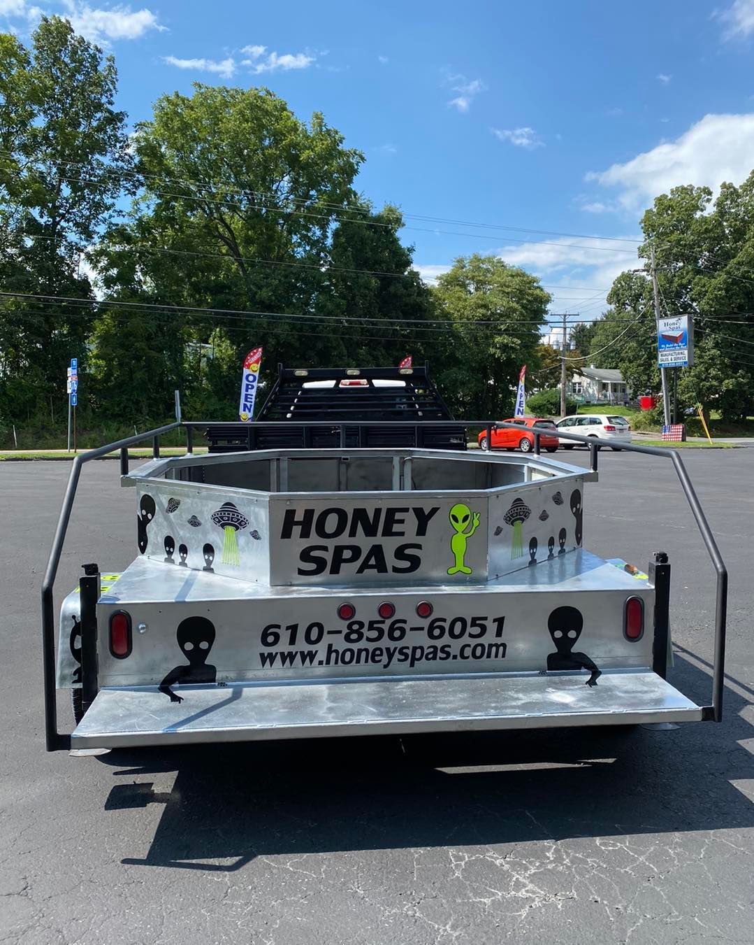 Honey Spas truck with alien decals and phone number 610-856-6051 parked in front of a building.