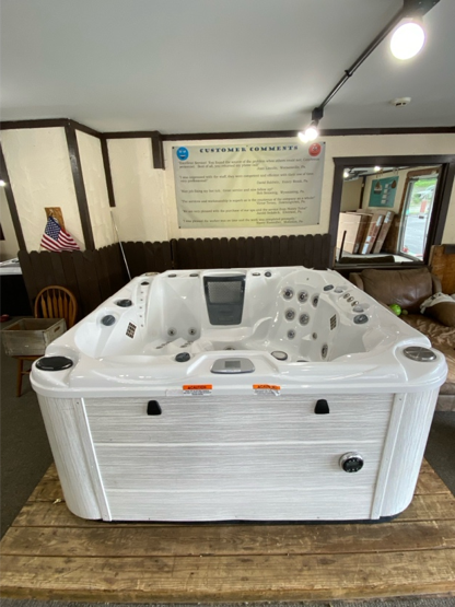 Hot tub with light brown wood paneling sits inside a garage with glass door.