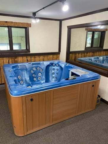 Hot tub with light brown wood paneling sits inside a garage with glass door.