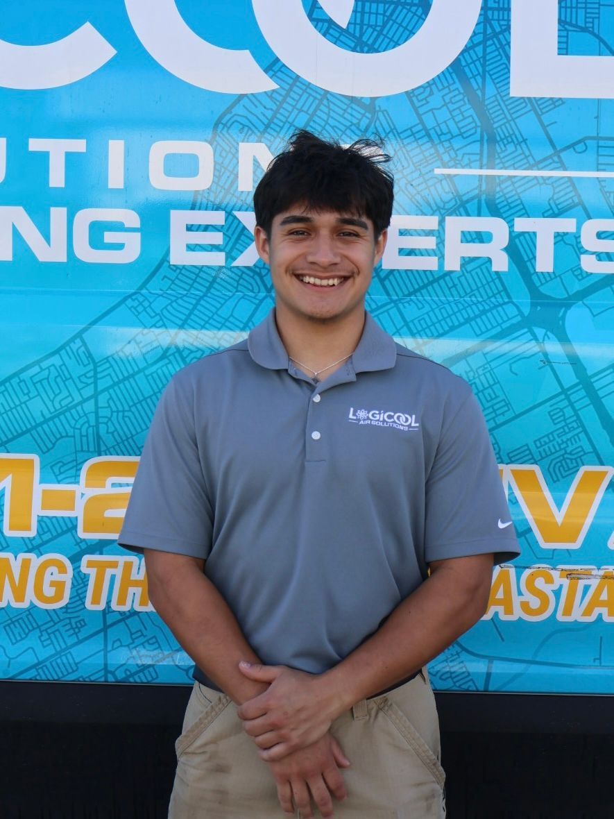 Smiling person in a gray polo shirt standing in front of a blue branded banner.