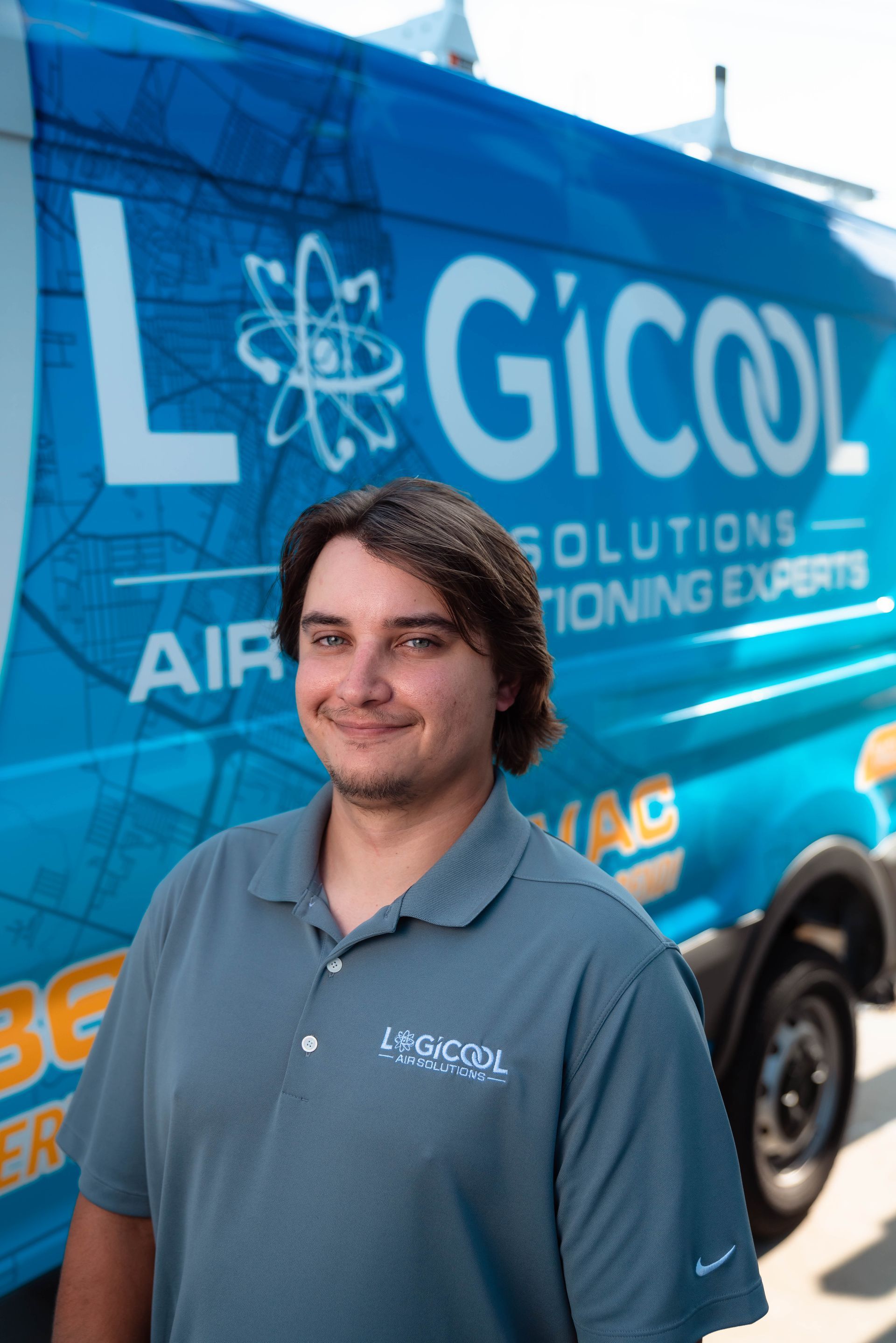 Man in blue polo standing before a blue Gicool air-conditioning service van