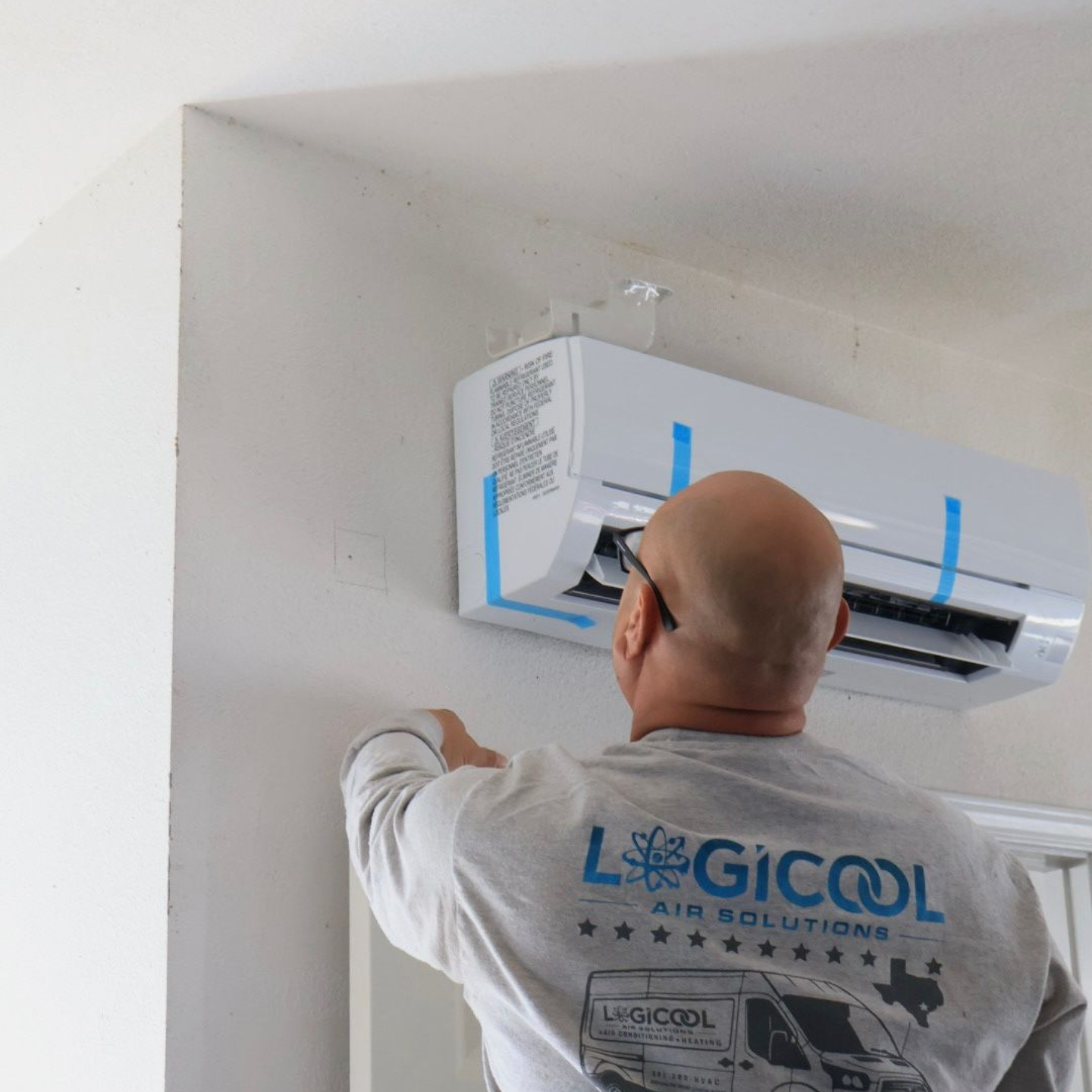 HVAC technician repairing residential air conditioner during spring AC maintenance service.