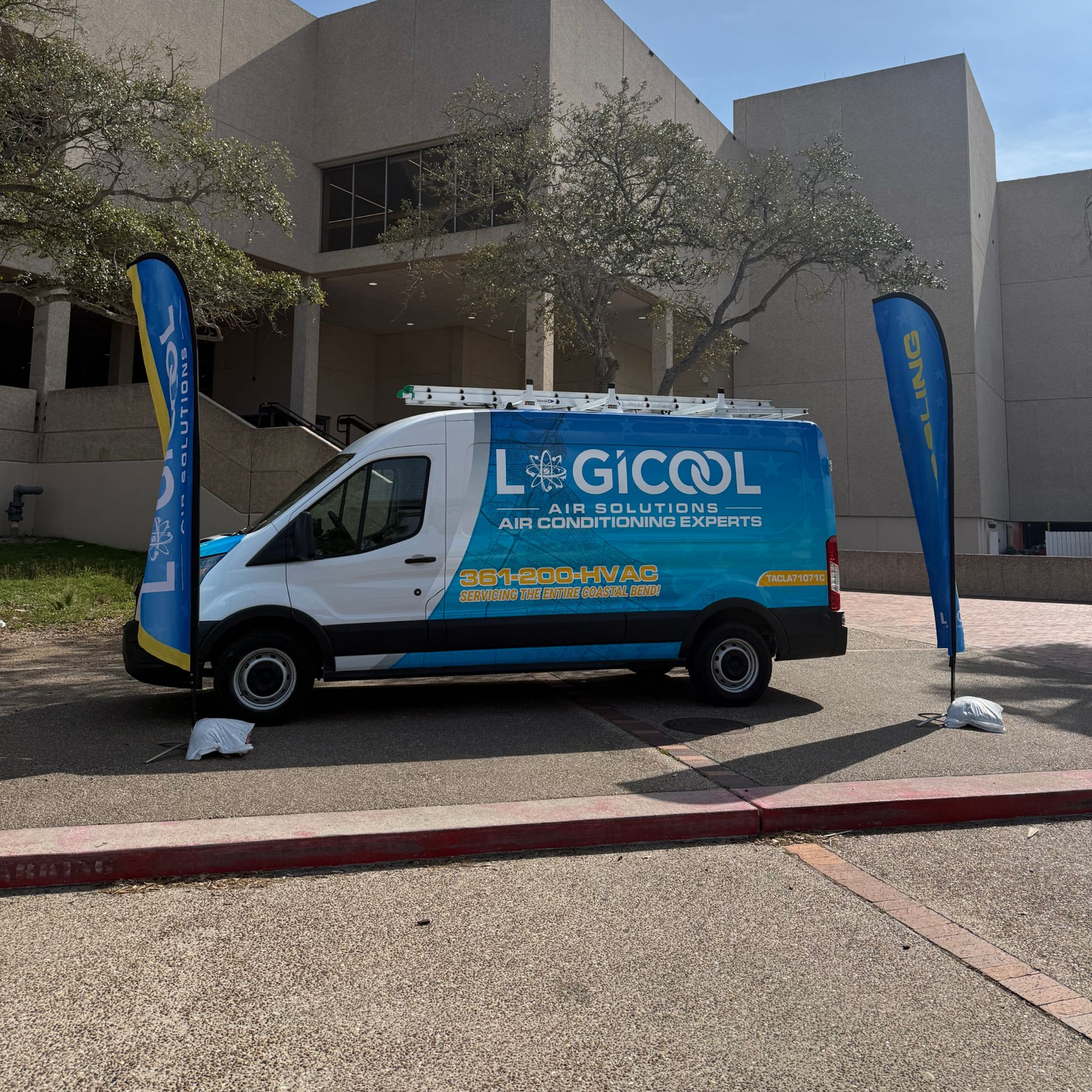 Blue-and-white LIGCOL service van parked outside a building with two blue flags