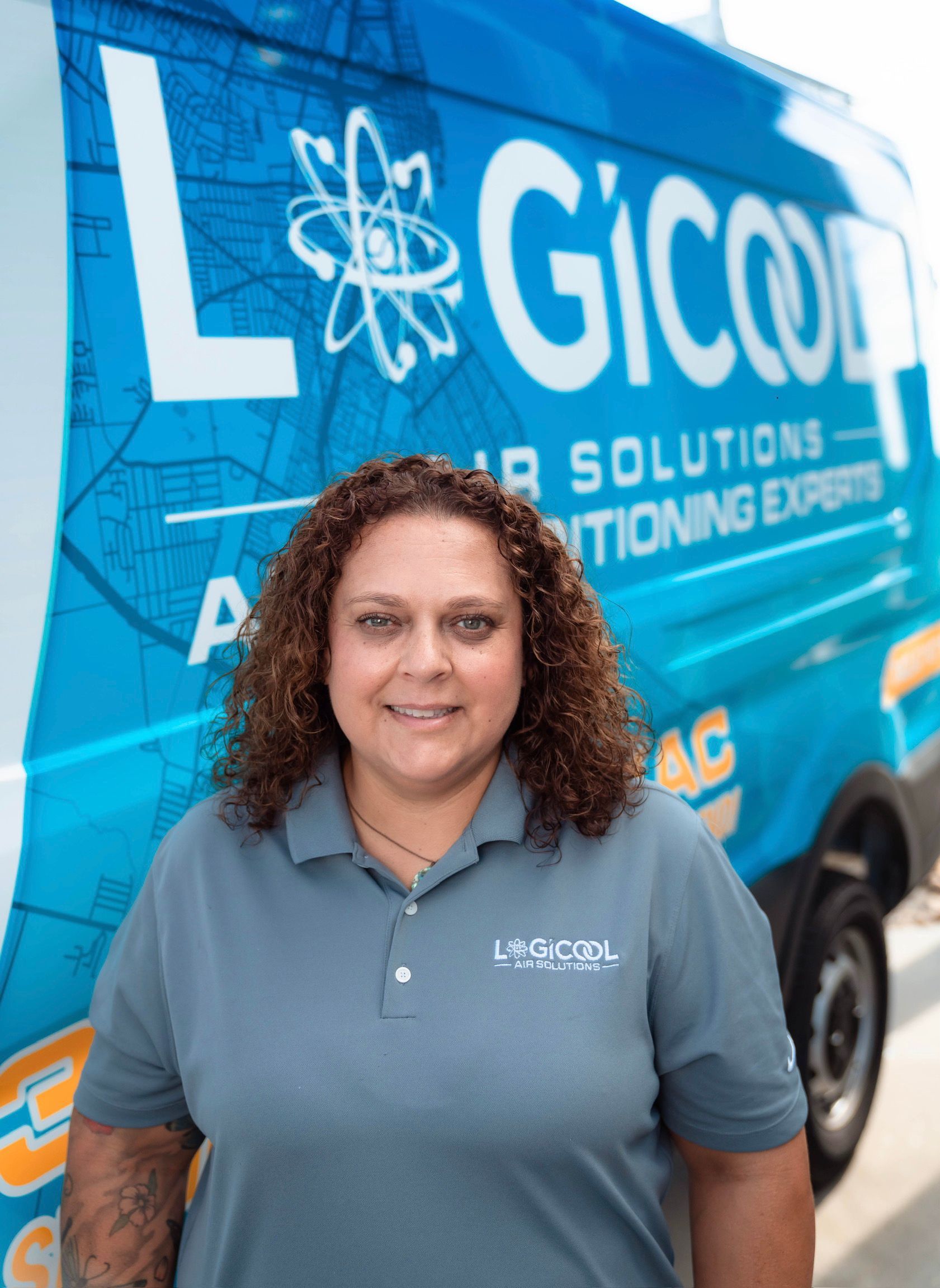 Woman in a gray polo standing in front of a blue LGICOL Air Solutions service van.