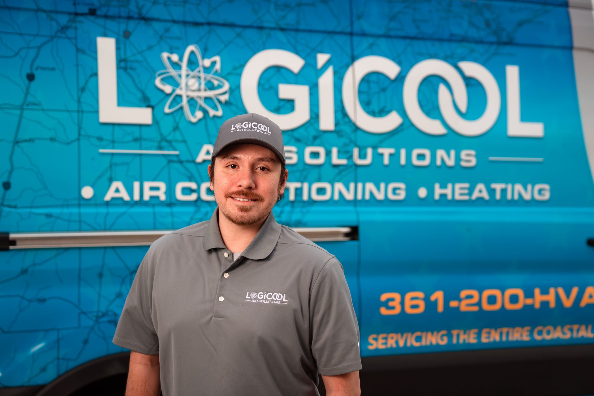 Man standing before a Logicool HVAC service truck with blue branding and logo