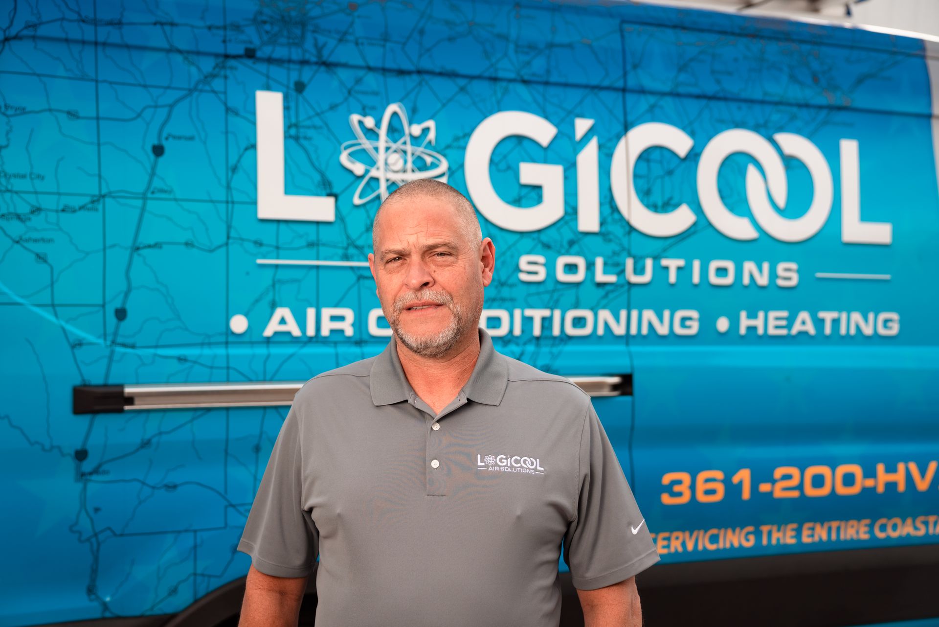 Man standing in front of a blue Logicool HVAC services van with company logo and text.