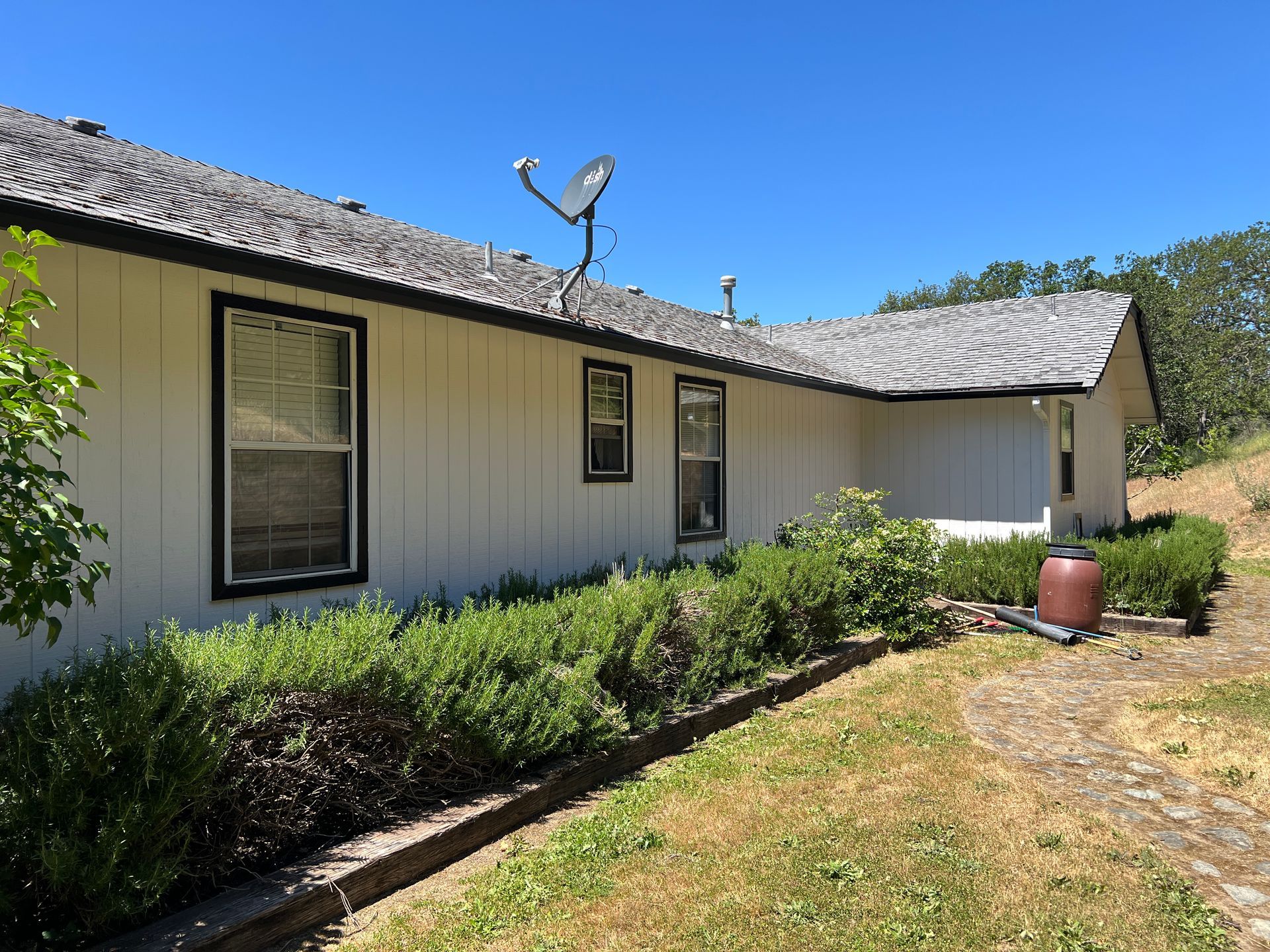 Garage front after repaint, white siding with black trim above the stone wainscot