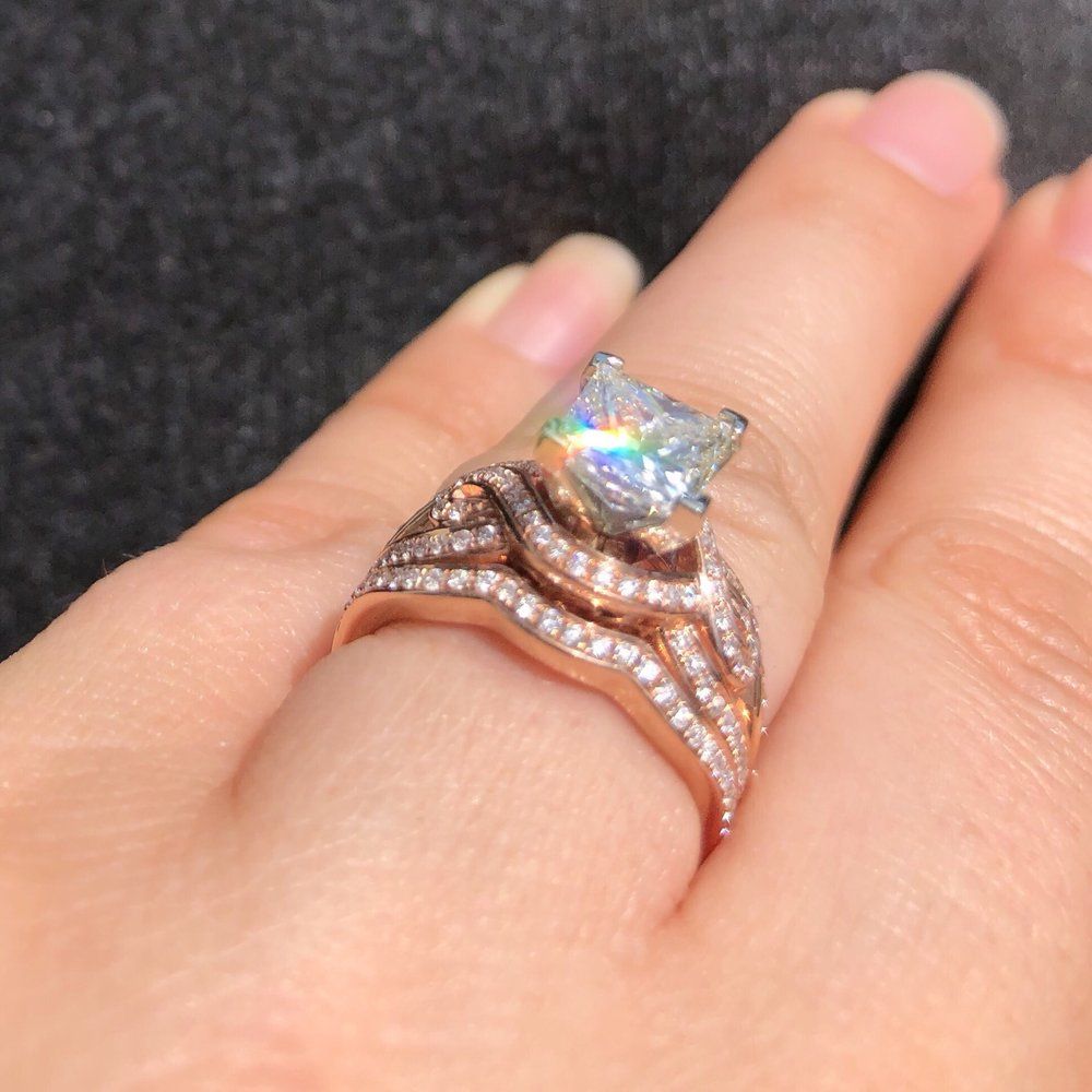 Close-up of a hand wearing a rose gold ring with a star-shaped iridescent gemstone.