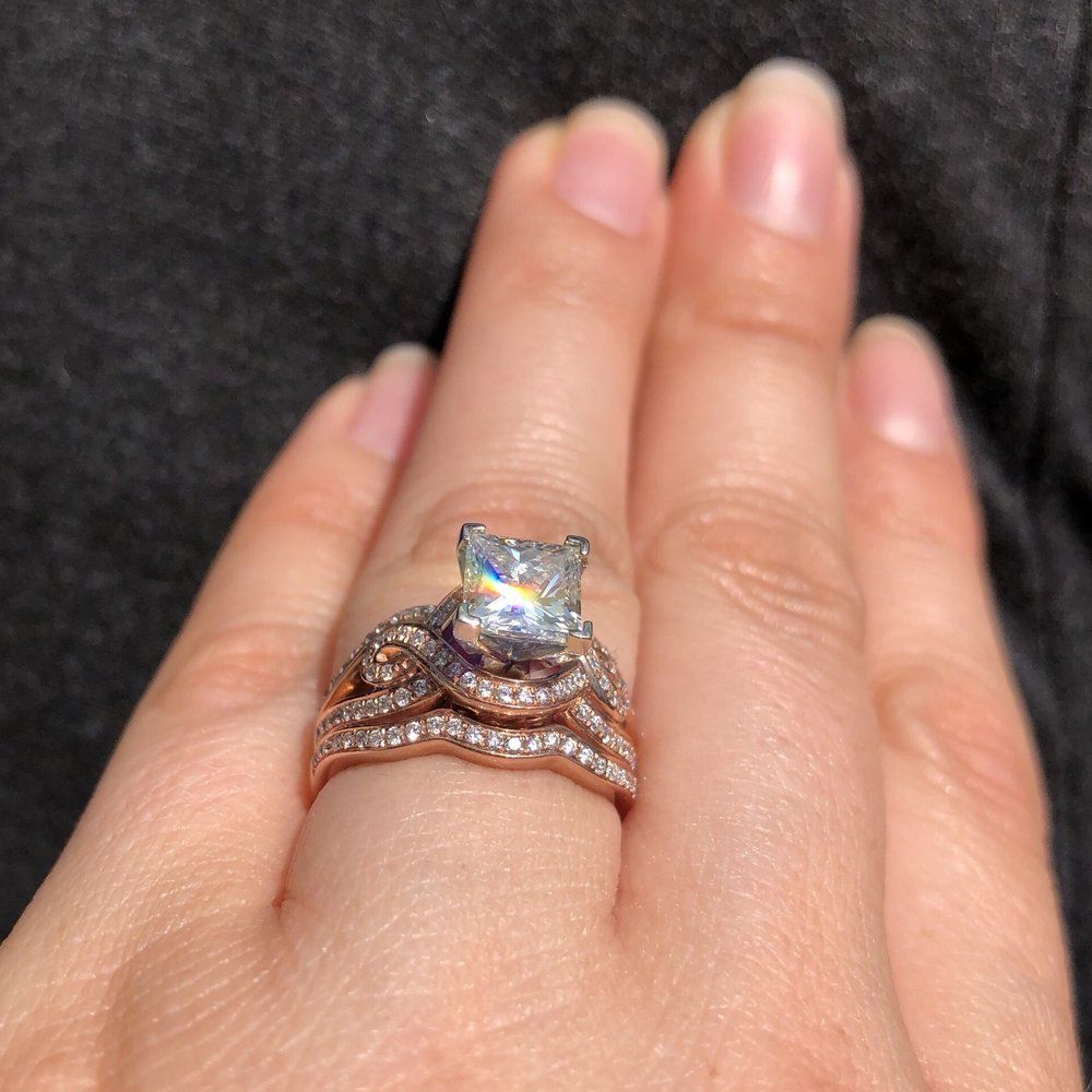 Hand wearing a sparkling silver ring set with a clear gemstone and matching band