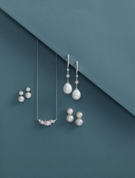 A necklace and earring set with pearls on a blue surface