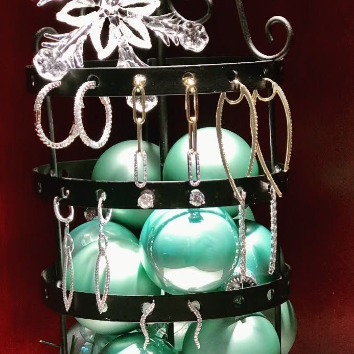Mint-green egg ornaments hanging on a black metal rack with a silver bow topper