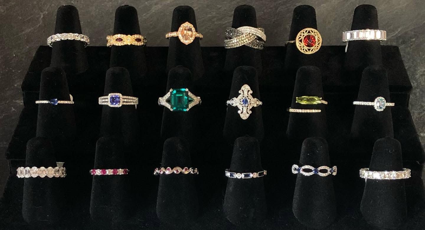 Velvet display of assorted rings with gemstone and metallic designs on black stands