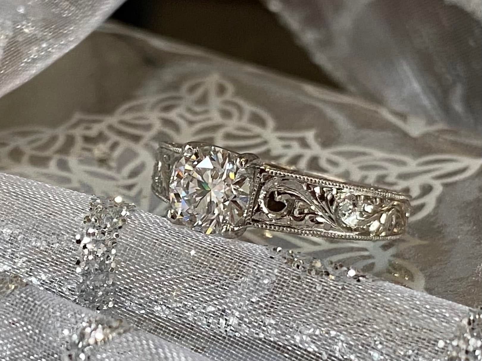 Ornate silver ring with a diamond resting on a white lace fabric background
