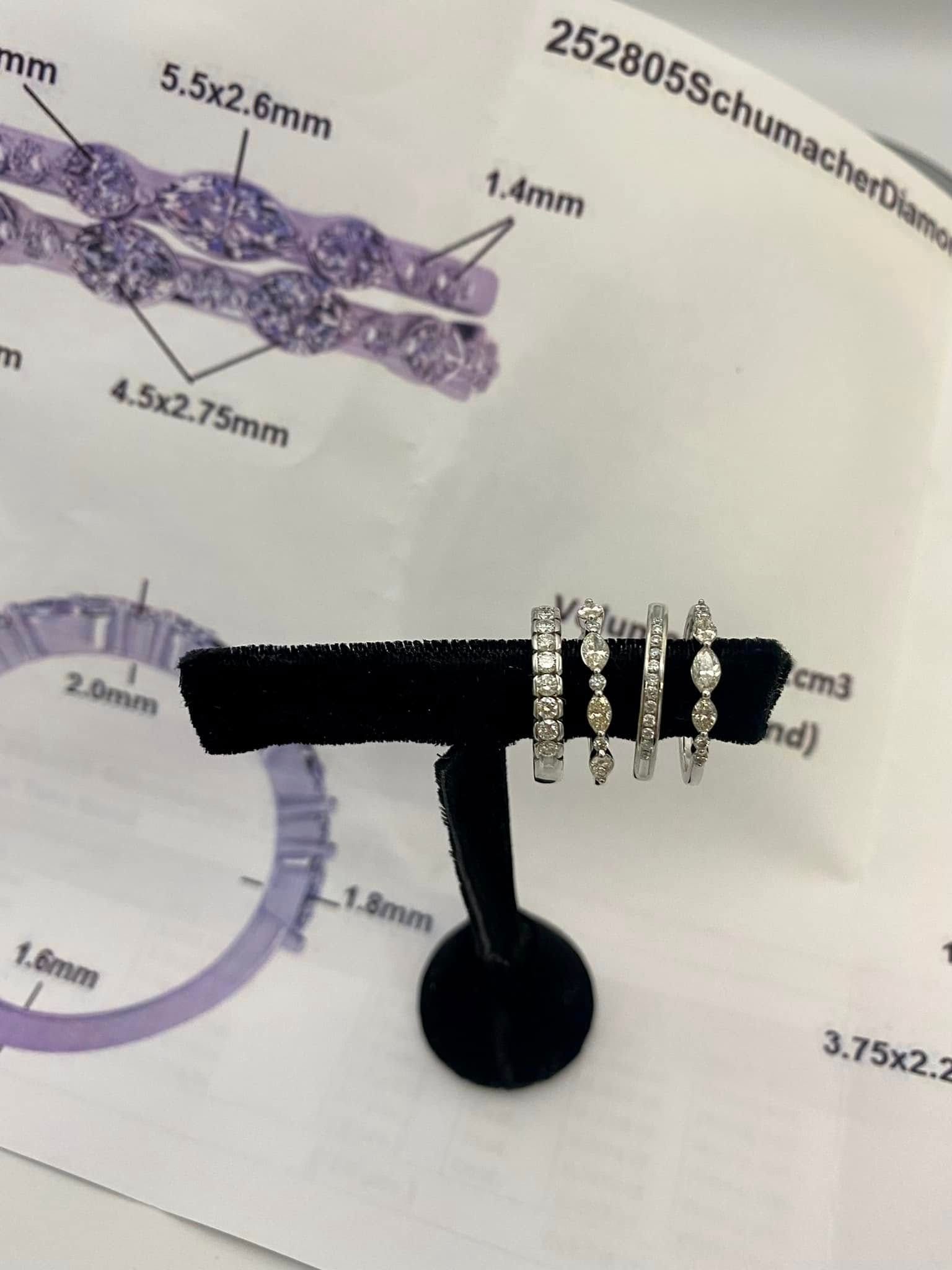 Black jewelry display stand holding three silver dangling earrings on a patterned background.