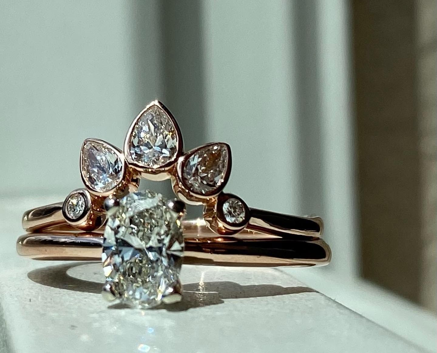 Rose gold diamond engagement ring with a marquise center stone and leaf-shaped halo on a windowsill