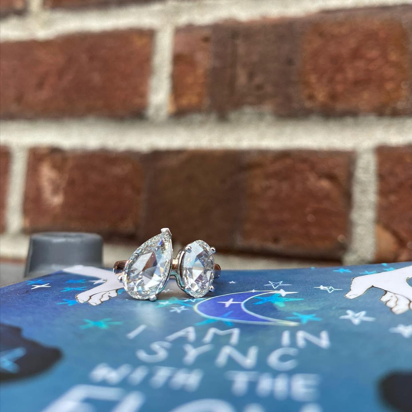 Two silver rings on a blue starry book cover in front of a brick wall