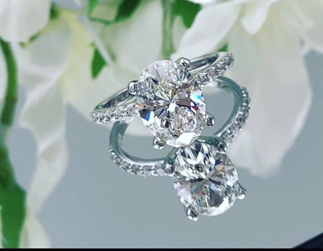 Crystal engagement ring with three large clear stones on a soft white floral background