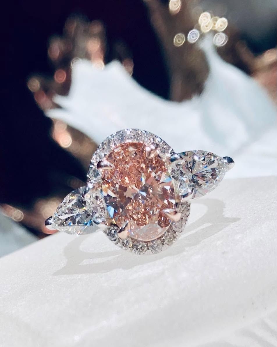 Close-up of a rose-gold diamond ring with marquise side stones on a white display cushion
