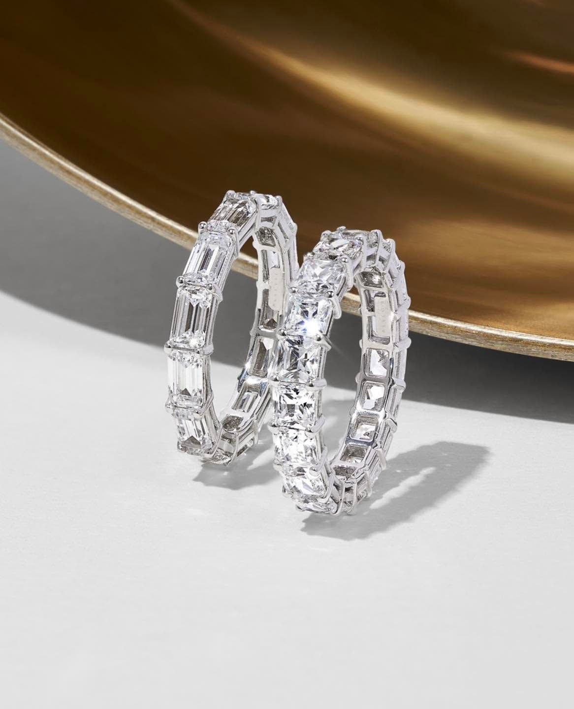 Pair of clear crystal hoop earrings on a white surface with a gold-toned background