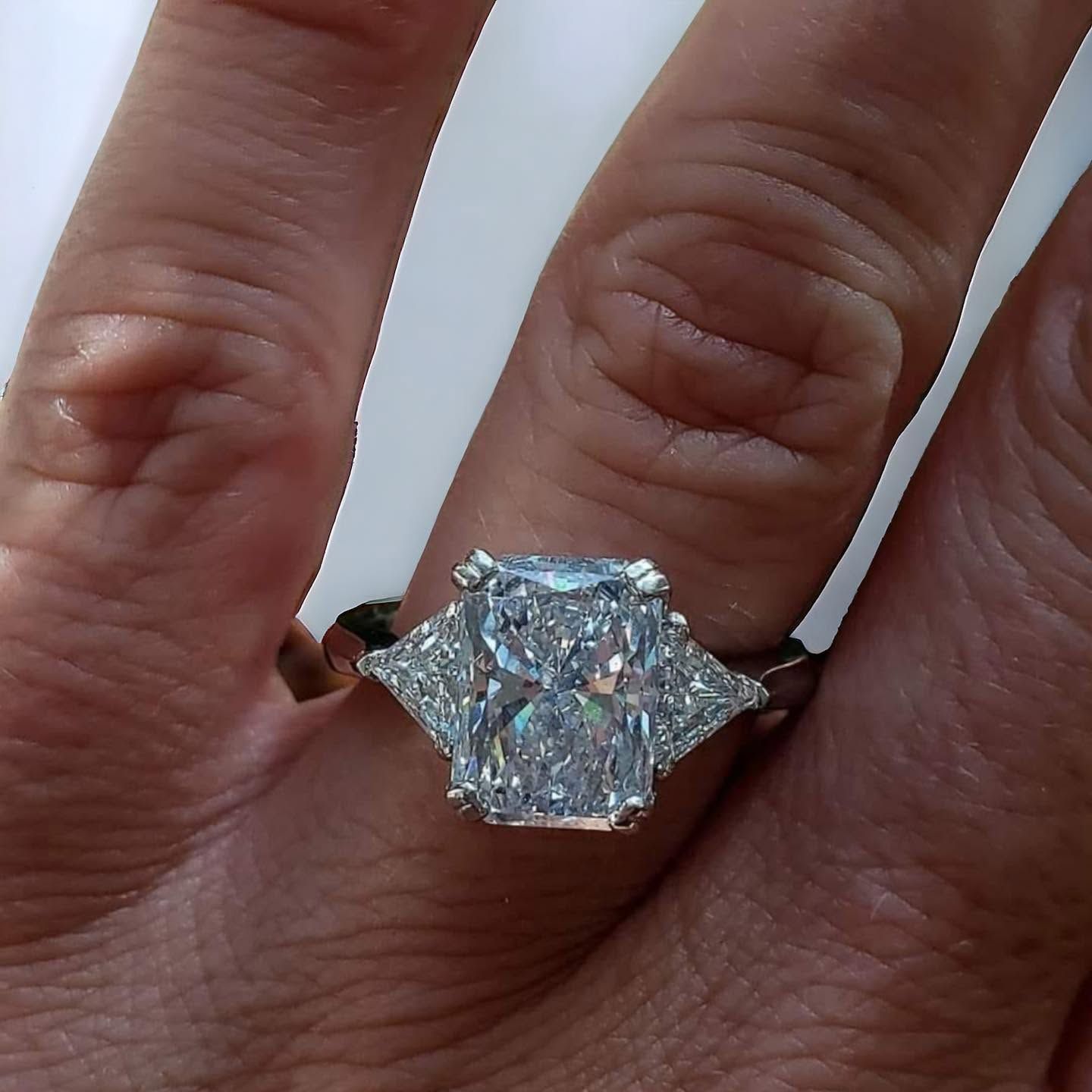Close-up of a hand wearing a large sparkling clear gemstone ring on a silver band