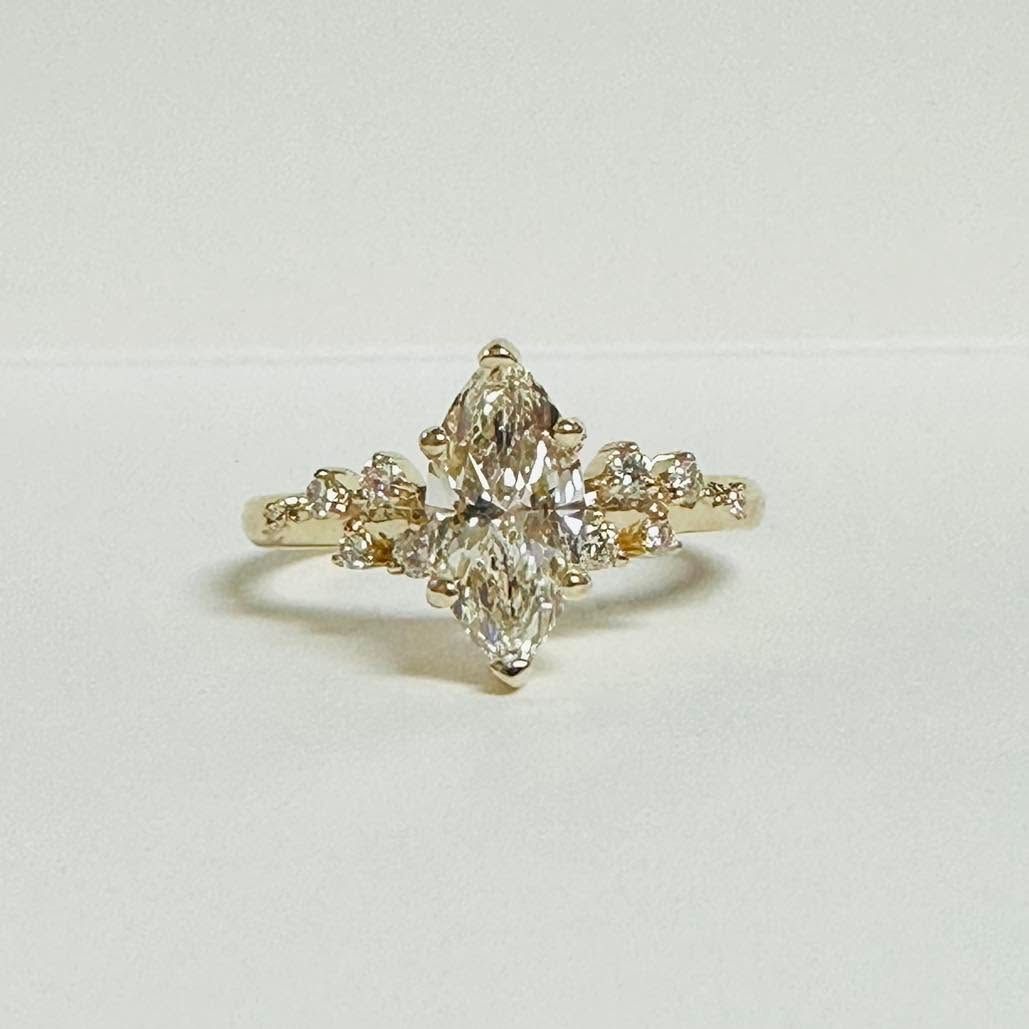 Gold and clear gemstone ring with a marquise-shaped center stone on a white background