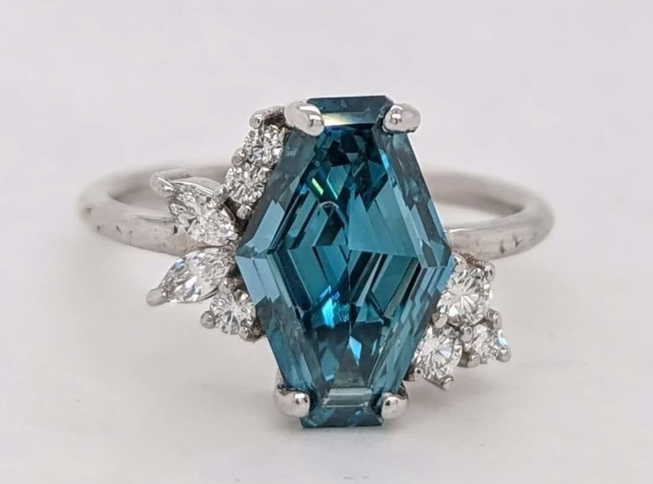 Silver ring with large blue hexagonal gemstone and small clear side stones