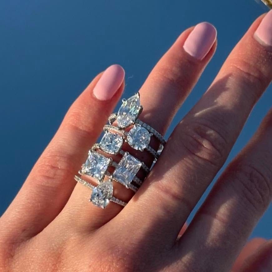 Hand with pink nails wearing a sparkling silver ring against a blue sky