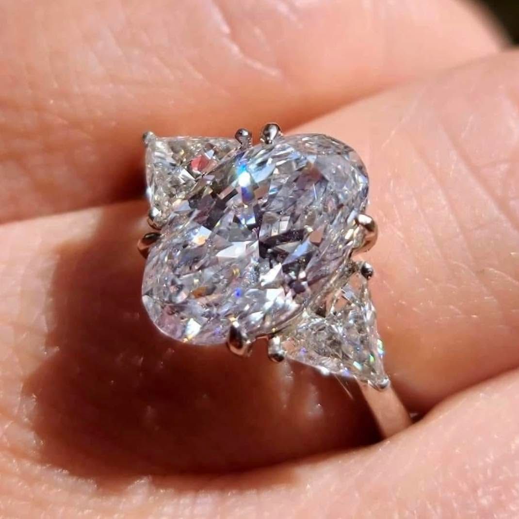 Close-up of a large diamond ring with a silver setting held between fingers