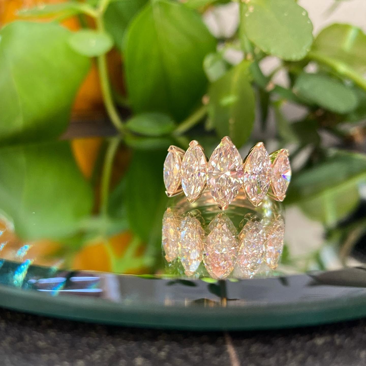 Small jeweled crown reflecting on a glossy black surface with green leaves in the background