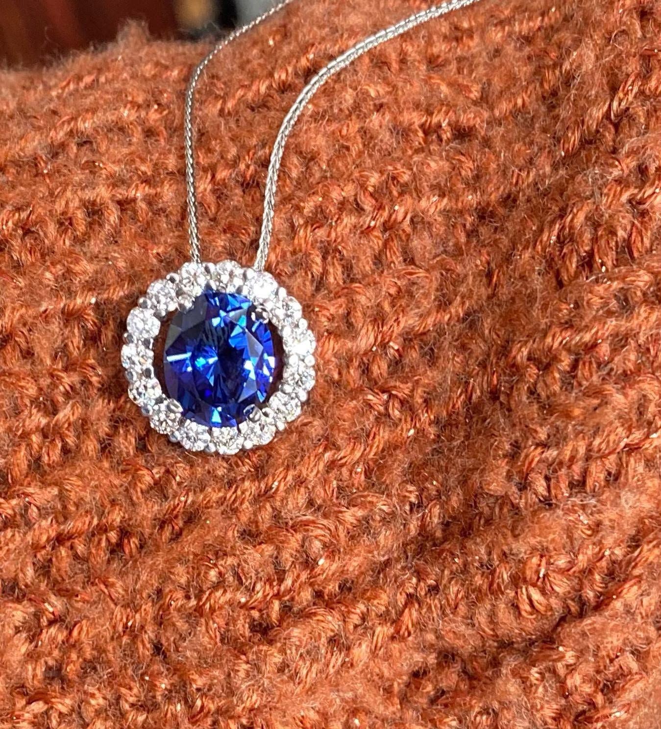 Silver necklace with a blue gemstone pendant on a brown textured fabric background
