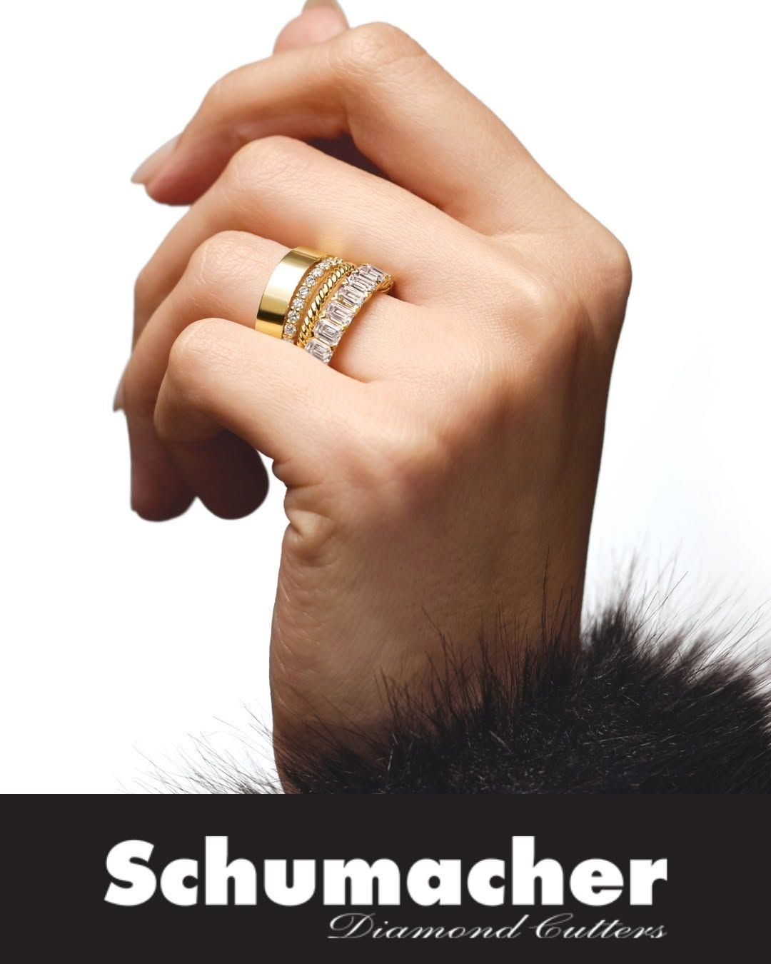 Close-up of a hand wearing gold and diamond rings above the Schumacher logo