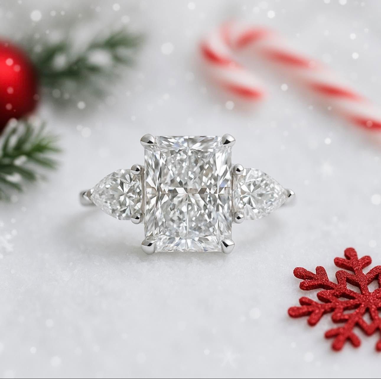 Diamond engagement ring on white snow with red holiday decorations and a candy cane.