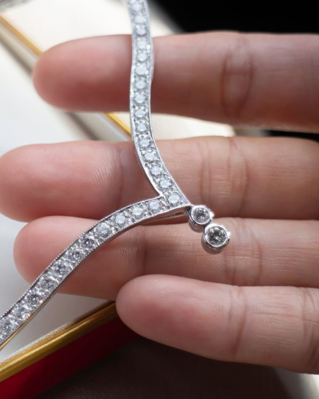 Diamond-studded silver necklace clasp held in a hand