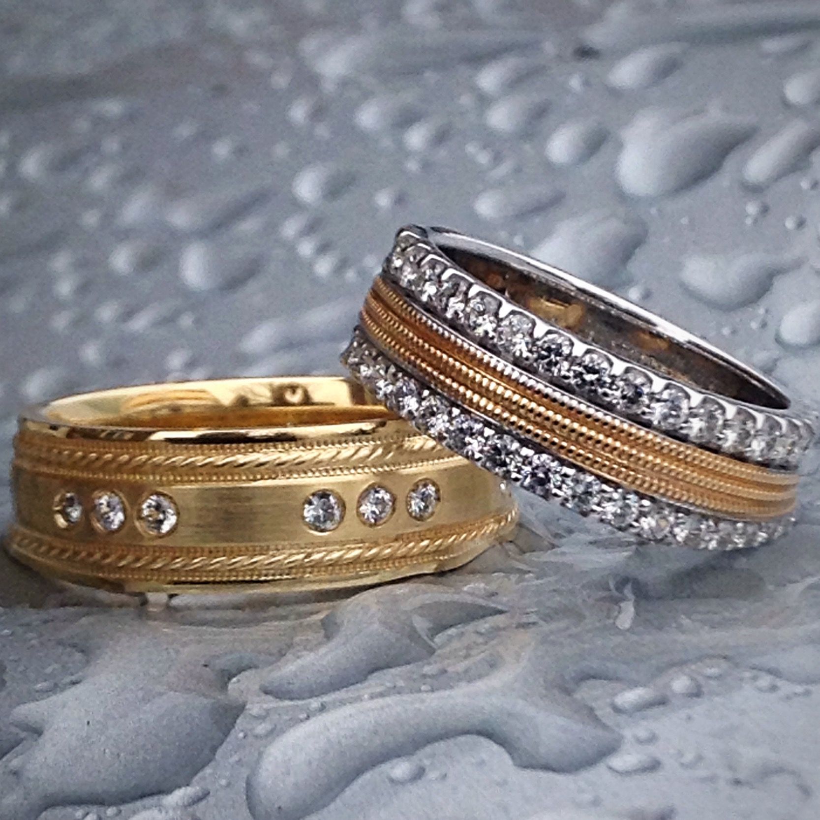 A gold and silver ring with diamonds sits on a wet surface