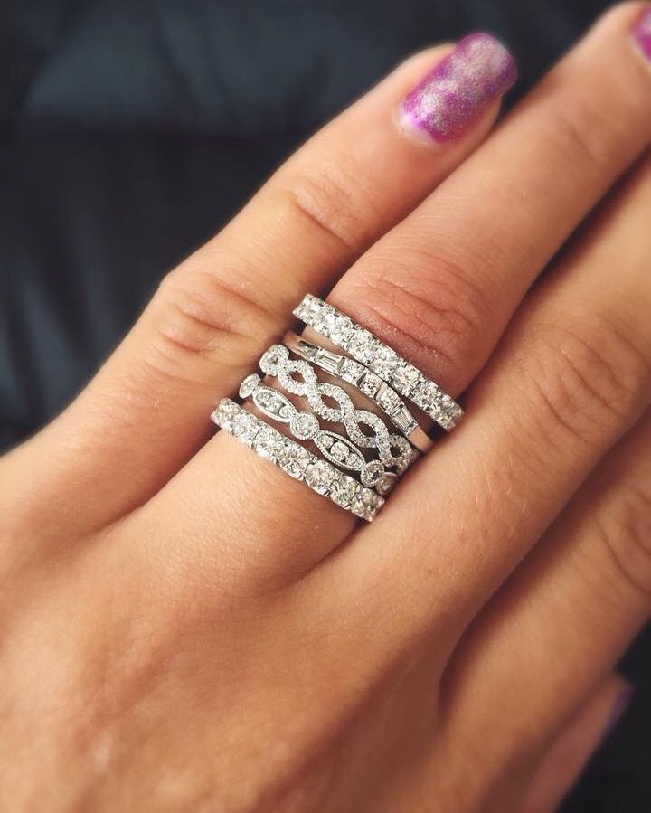Hand wearing a silver, diamond-studded ring on a finger with pink glitter nail polish