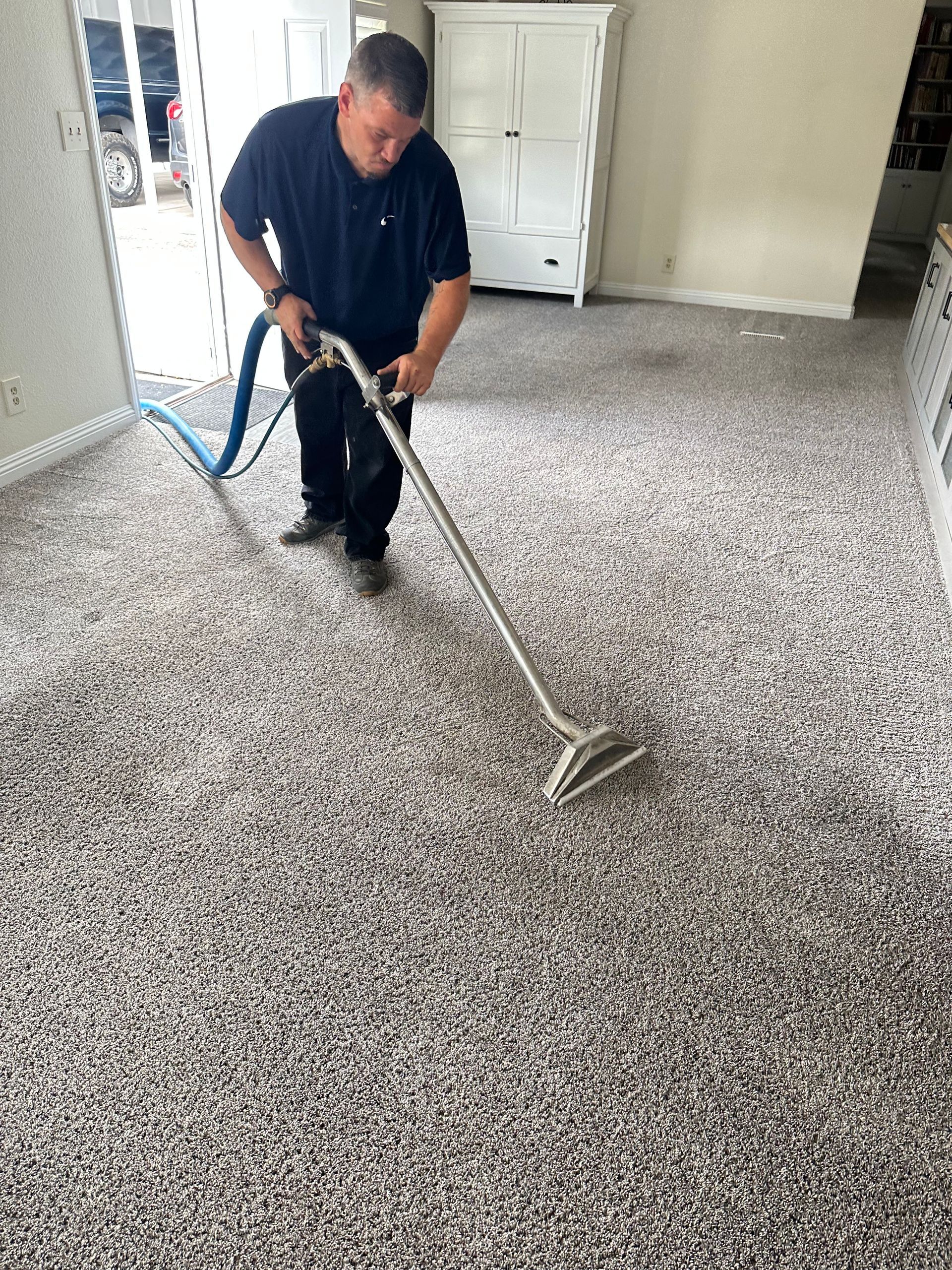 A man is using a vacuum cleaner to clean a carpet in a living room.