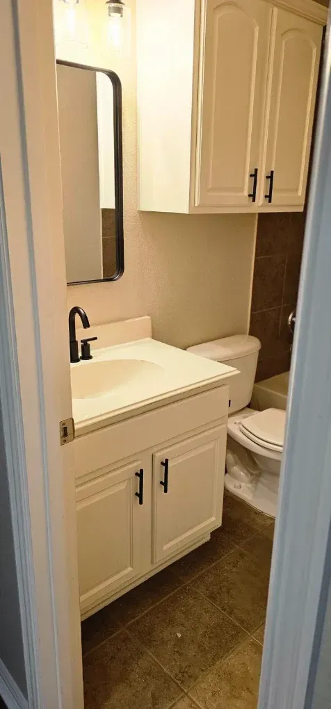 Small bathroom with white vanity, sink, mirror cabinet, and tan walls.