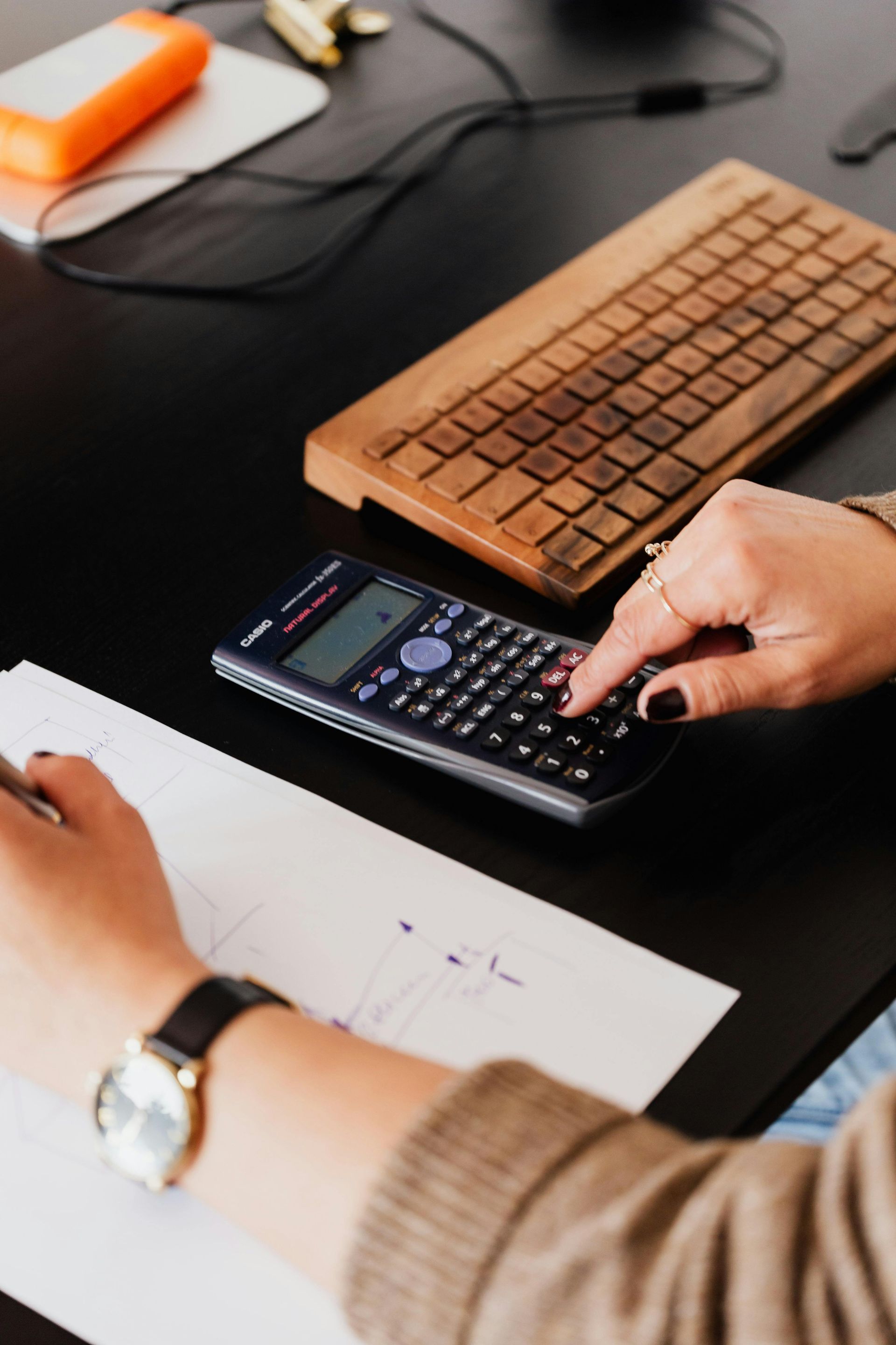 A person is using a calculator next to a keyboard