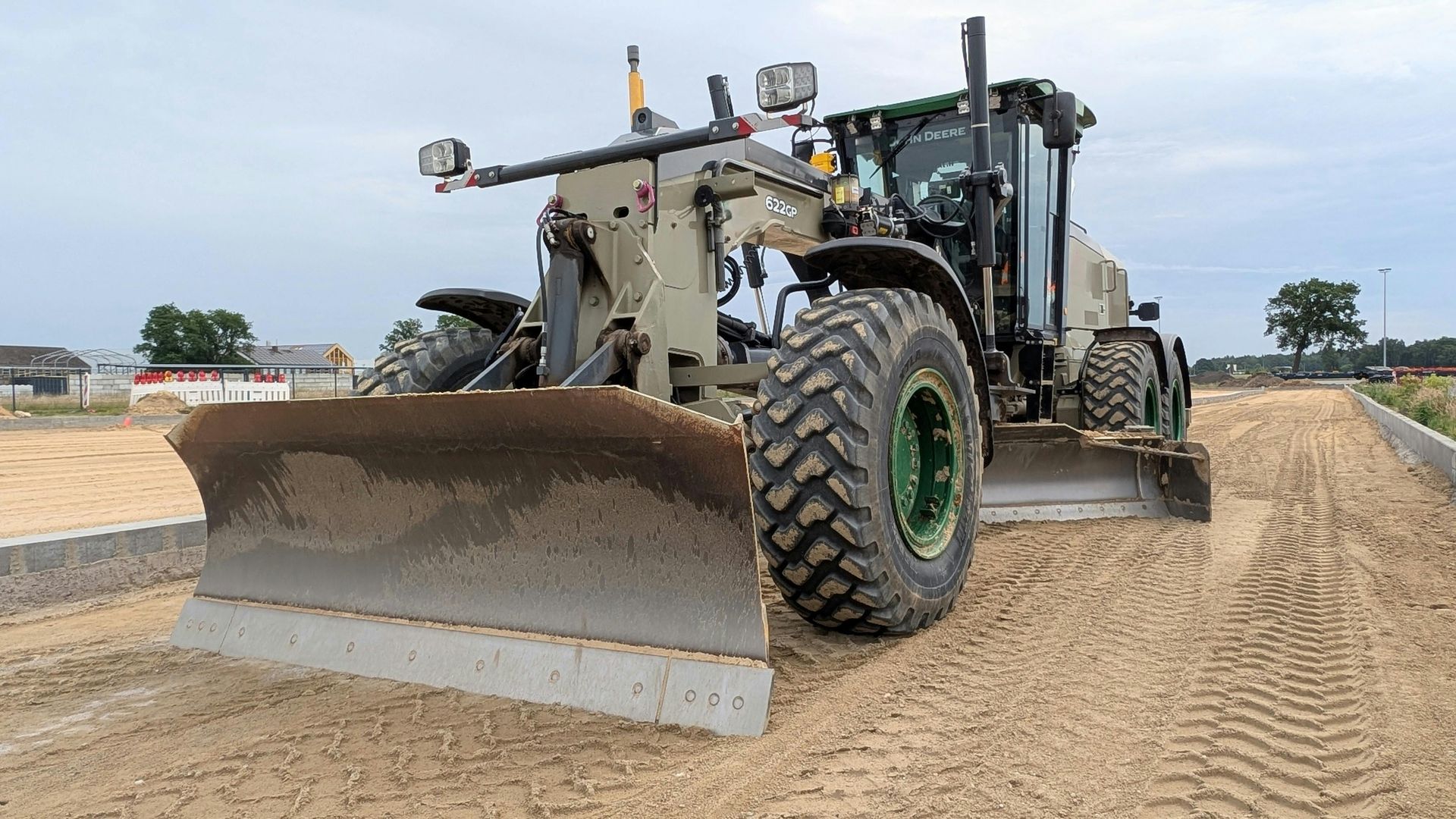 A bulldozer is carrying a large tree stump on a dirt road.