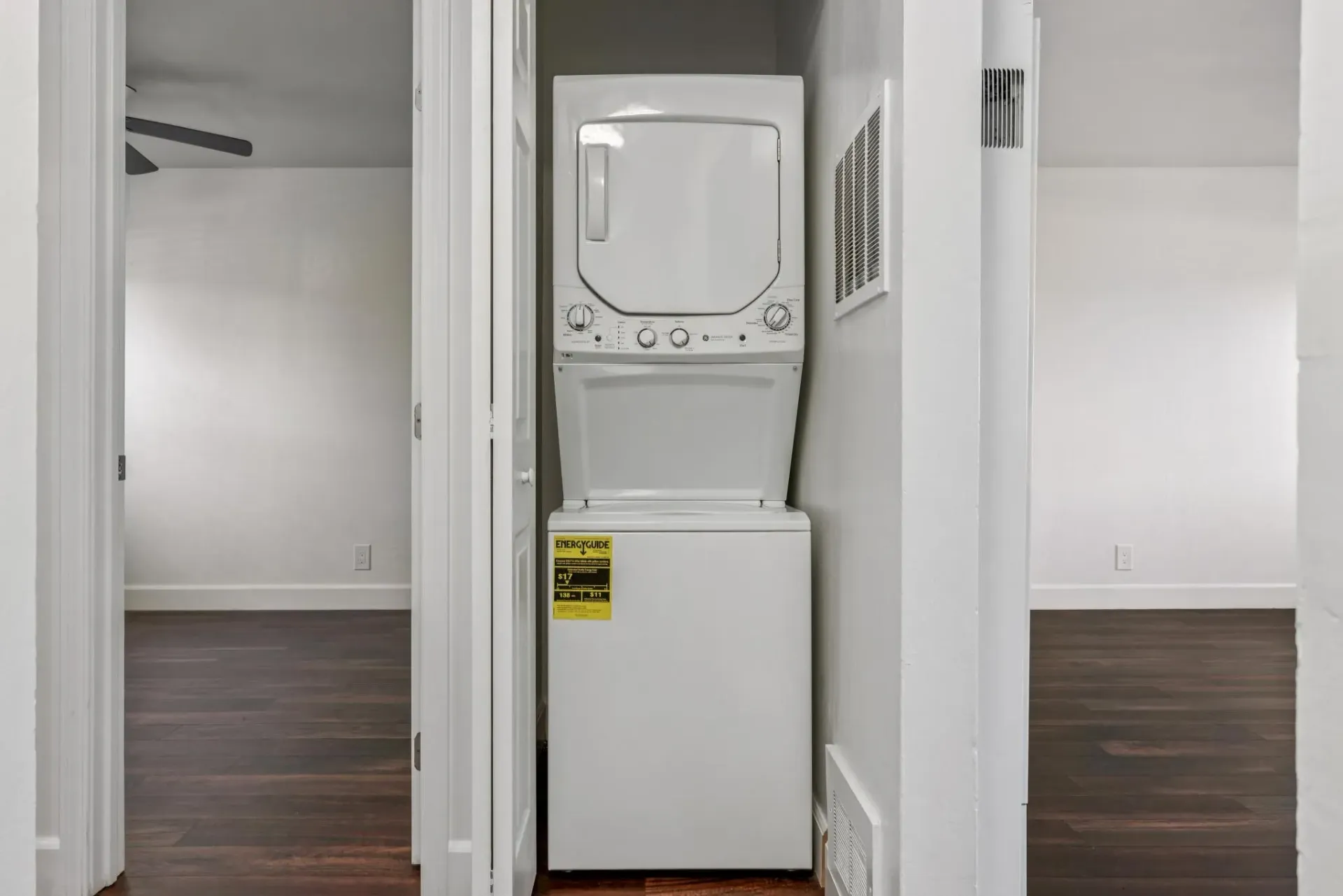 Stacked washer and dryer in a compact laundry closet with white walls.
